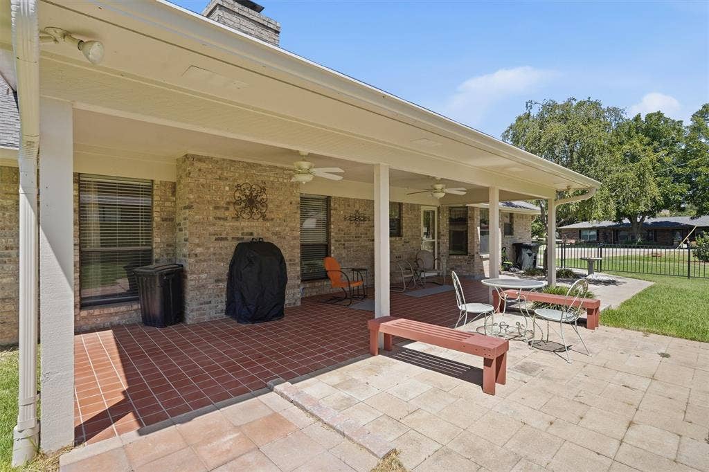5711 Cortez Drive, Granbury, TX 76049 Expansive covered patio featuring brick-laid flooring, multiple ceiling fans, and a brick exterior