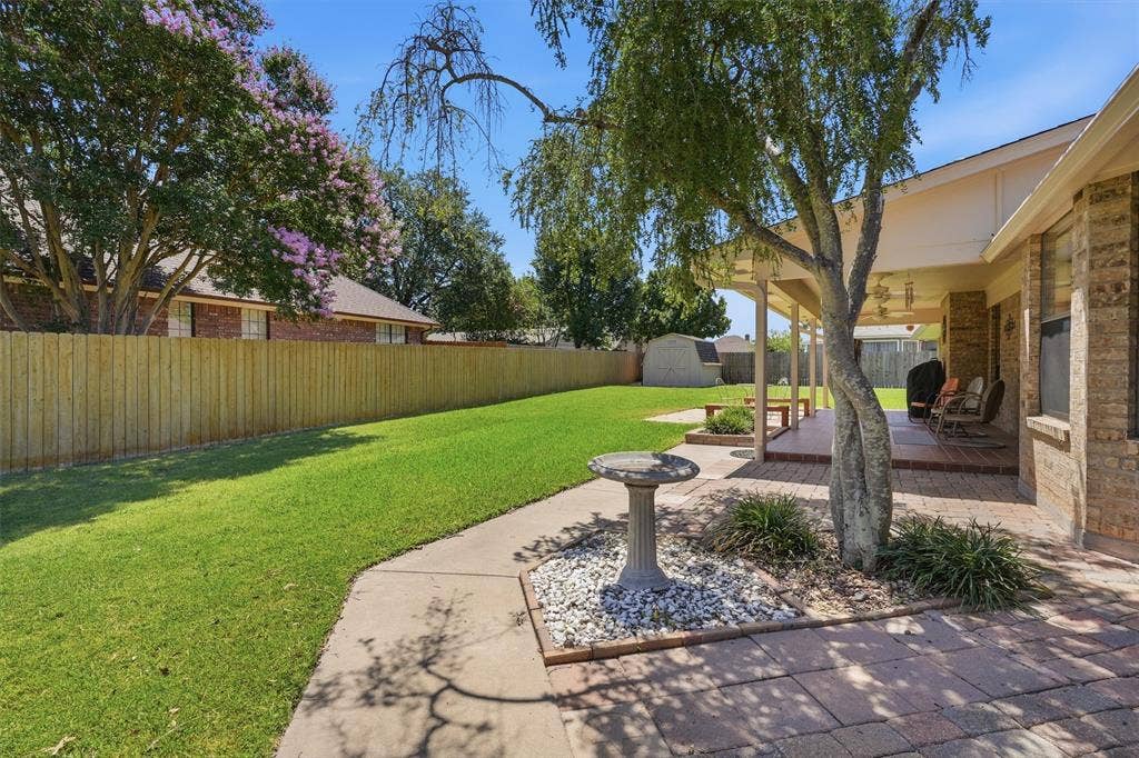 5711 Cortez Drive, Granbury, TX 76049 Expansive backyard featuring a manicured lawn, full privacy fence, and mature trees