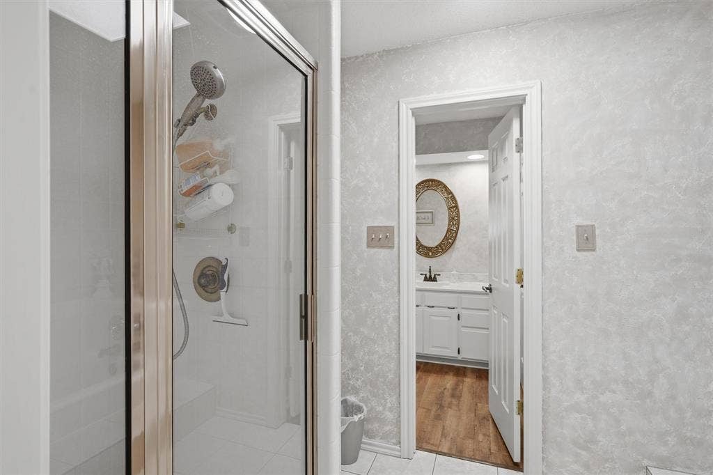 5711 Cortez Drive, Granbury, TX 76049 Glass-enclosed shower with a brushed nickel showerhead and bath/shower diverter