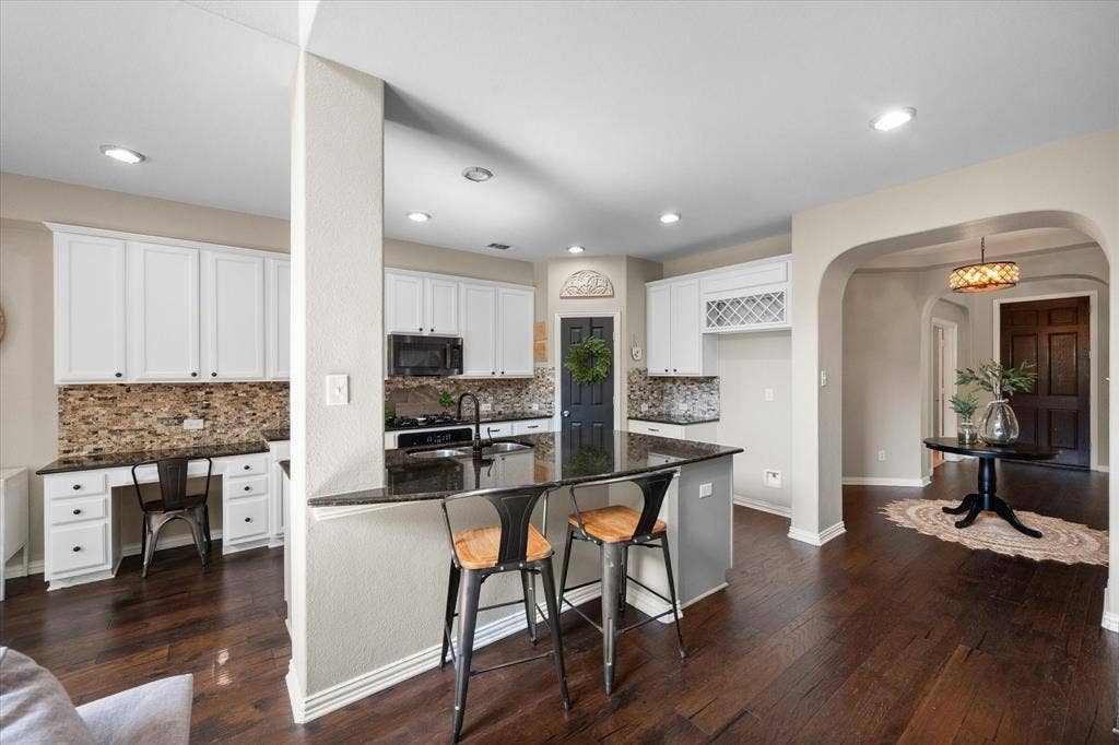 12032 Terrazzo Lane, Frisco, TX 75035 Kitchen with a built-in desk, custom cabinetry, granite countertops, and mosaic tile backsplash and pantry!