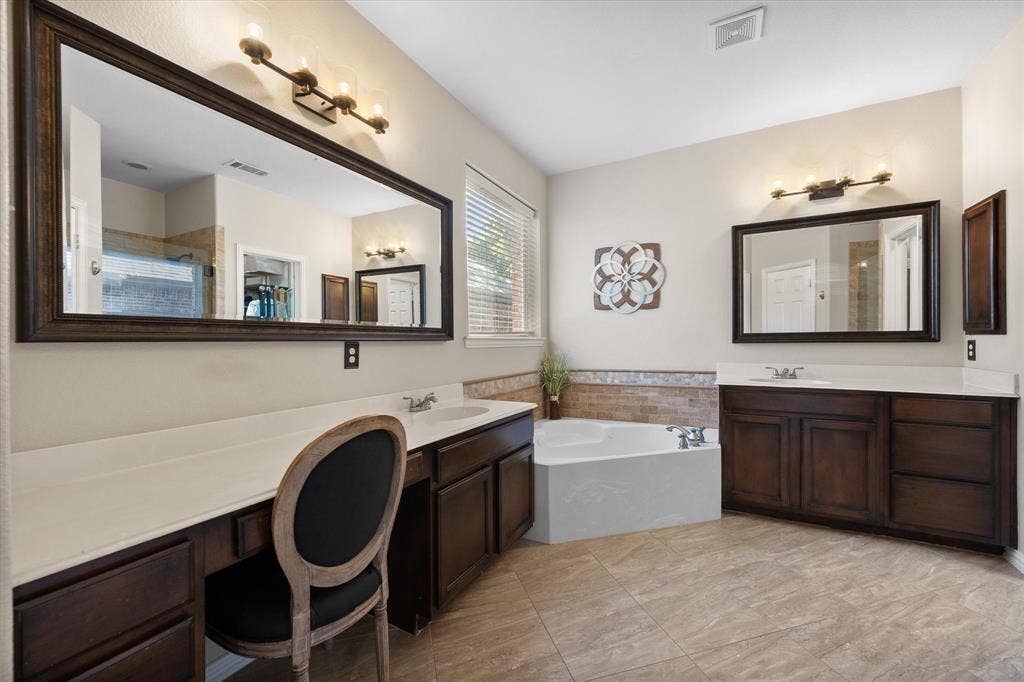 12032 Terrazzo Lane, Frisco, TX 75035 Spacious bathroom featuring a built-in vanity with dual sinks, an expansive mirror, and a corner soaking tub!
