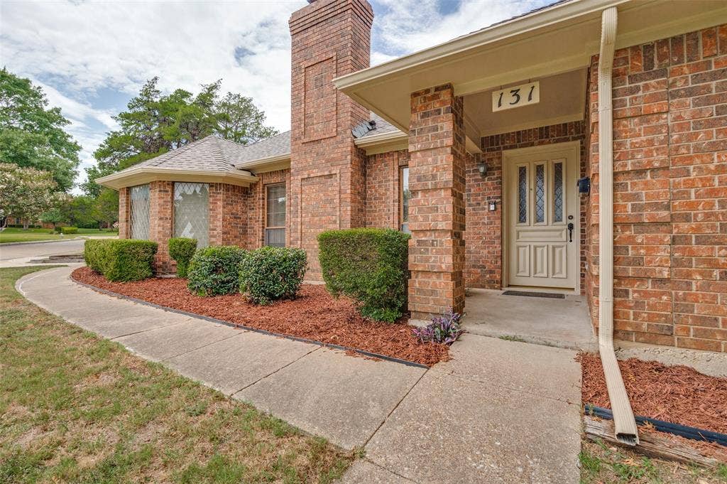 131 Honey Tree Lane, DeSoto, TX 75115 Brick exterior featuring a covered entry with a paneled front door, an address number above the door, and a bay window