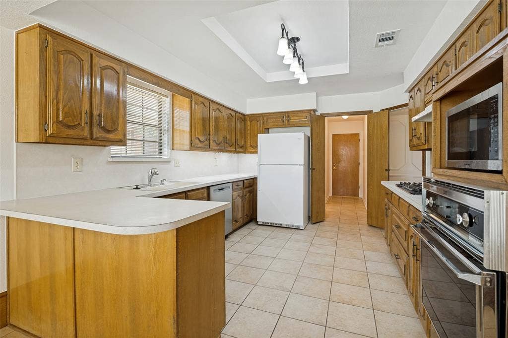131 Honey Tree Lane, DeSoto, TX 75115 Kitchen featuring extensive wood cabinetry, light-toned countertops, and tile flooring