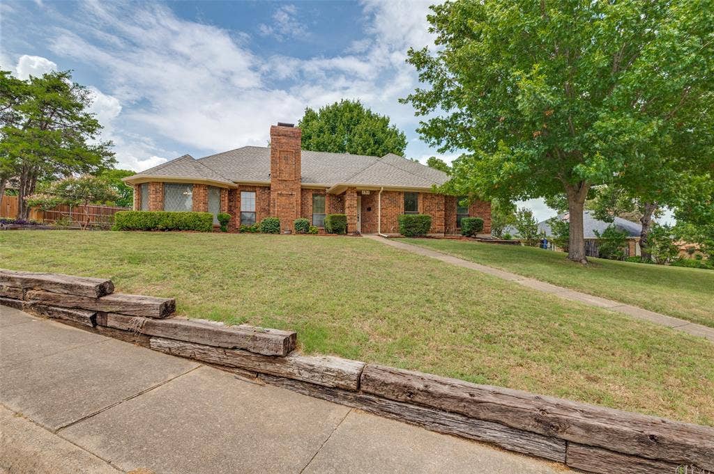 131 Honey Tree Lane, DeSoto, TX 75115 Brick exterior residence with a prominent chimney, an attached garage, a walkway, and a landscaped front yard featuring mature trees
