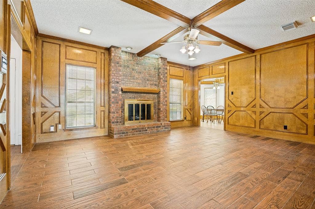 131 Honey Tree Lane, DeSoto, TX 75115 Living area featuring wood-finish flooring, a brick fireplace with a wood mantel, and wood paneling