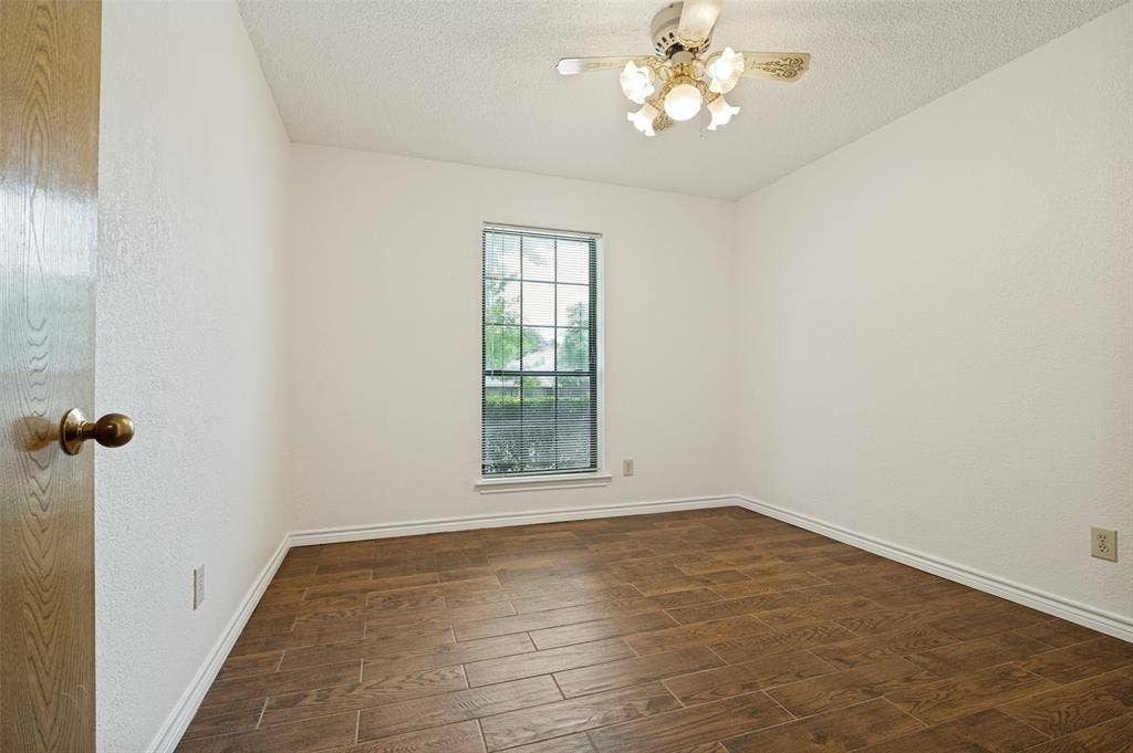 131 Honey Tree Lane, DeSoto, TX 75115 Interior room featuring wood-finish flooring, white baseboards, and a single window with exterior landscaping visible