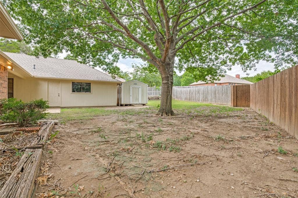 131 Honey Tree Lane, DeSoto, TX 75115 Expansive backyard featuring a mature shade tree, a separate storage shed, and durable wood fencing