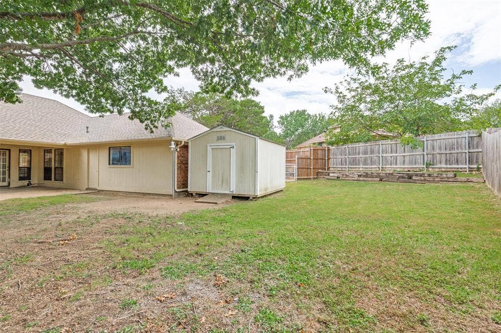 131 Honey Tree Lane, DeSoto, TX 75115 Expansive backyard featuring a storage shed, wood privacy fencing, and a concrete patio