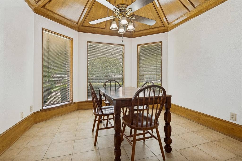 131 Honey Tree Lane, DeSoto, TX 75115 Bay window dining area with a coffered wood-finish ceiling, tile flooring, and a ceiling fan with integrated lighting