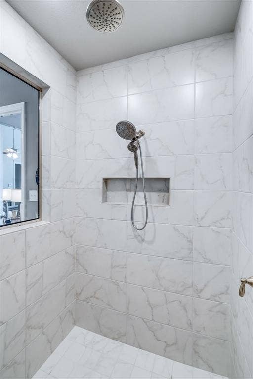 Shower enclosure featuring white marble-look tile walls and floor