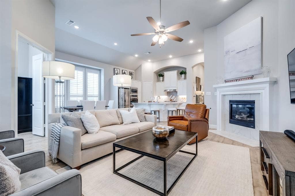 Living area featuring a fireplace with a white mantel, recessed lighting, and a ceiling fan