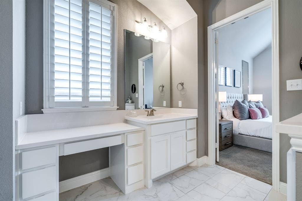 Bathroom vanity featuring a single basin, white cabinetry, and an integrated dressing table with drawers