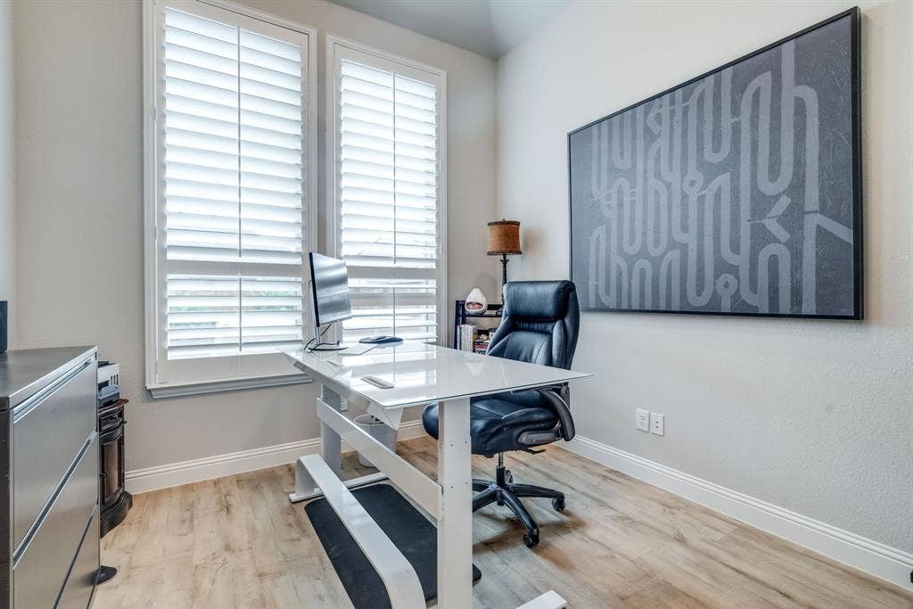 Room featuring wood-finish flooring, light-toned walls, and white plantation shutters on dual windows