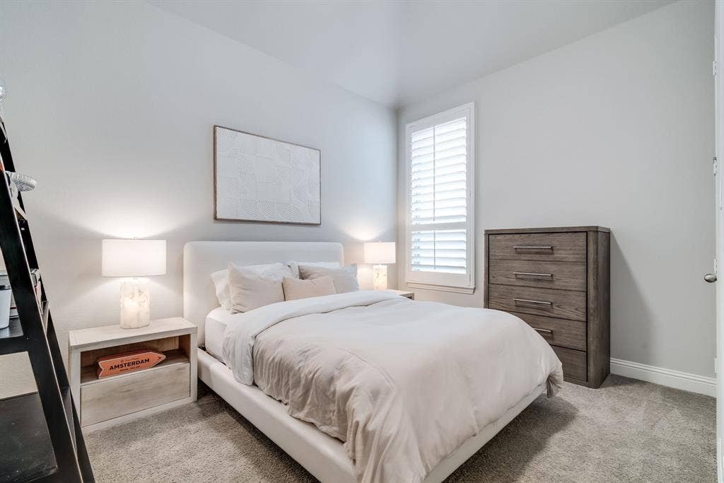 Carpeted room with a window featuring white plantation shutters, bright white baseboards, and light gray wall paint
