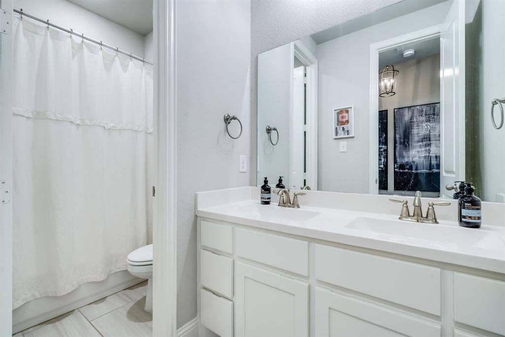Bathroom featuring a double vanity with white cabinetry, white countertops, and brushed nickel fixtures