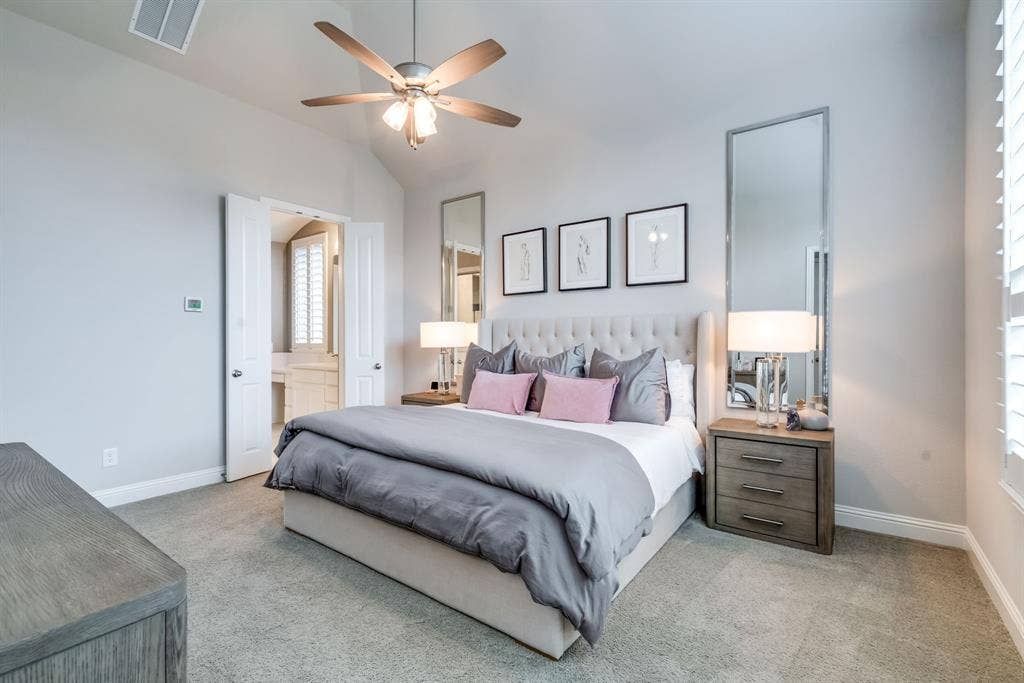 Vaulted ceiling room featuring a ceiling fan, plush carpeting, and a built-in upholstered headboard