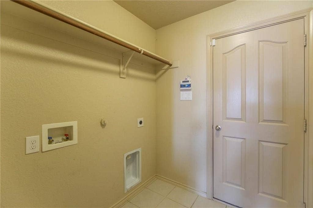 Utility area with tile flooring and a built-in hanging rod