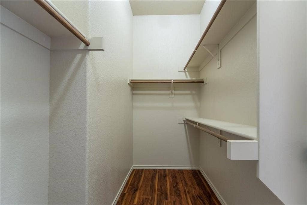 Walk-in closet featuring wood-finish flooring, multiple shelving units, and integrated hanging rods