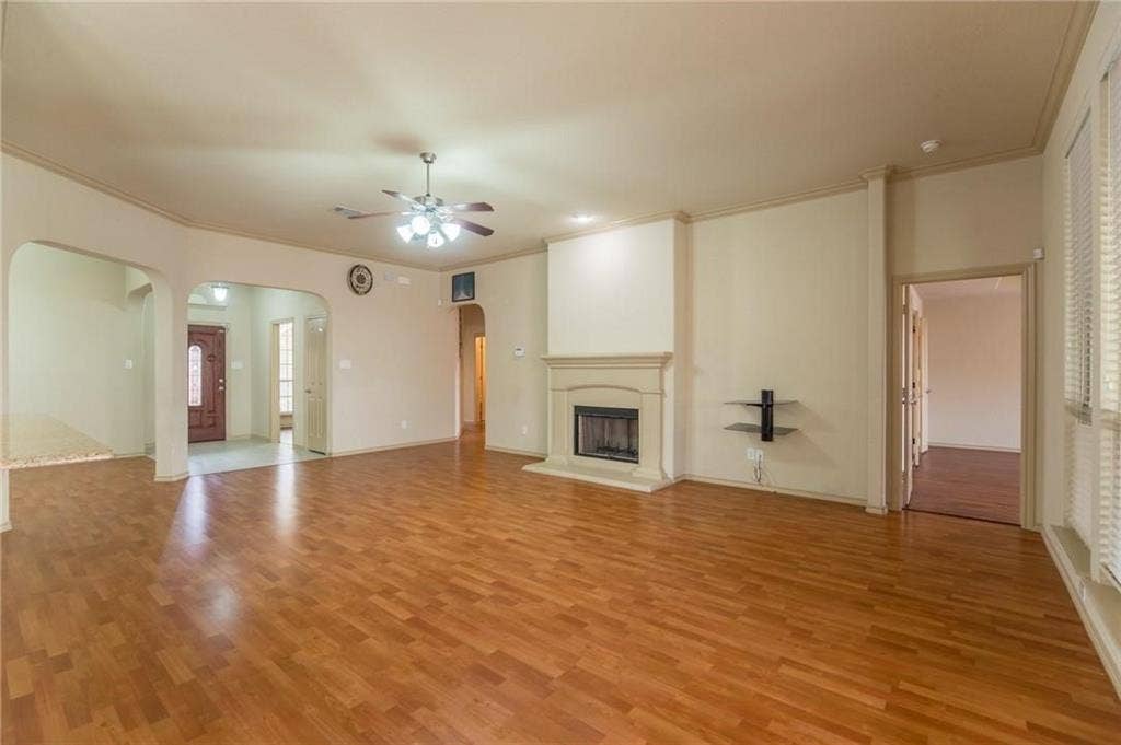 Spacious living area featuring wood-finish flooring and a ceiling fan with integrated lighting