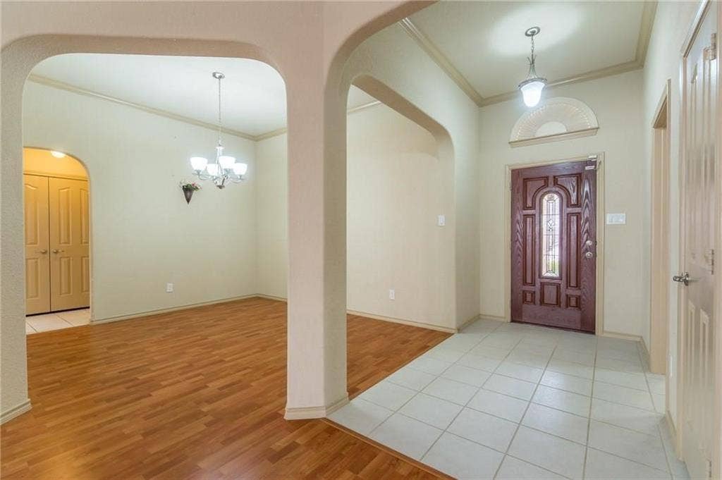 Foyer featuring a decorative front door with an arched transom window, ceramic tile flooring, and a pendant light fixture