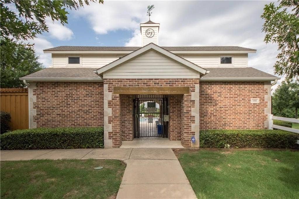 Brick and siding building featuring a prominent gabled entrance with an ornamental weathervane