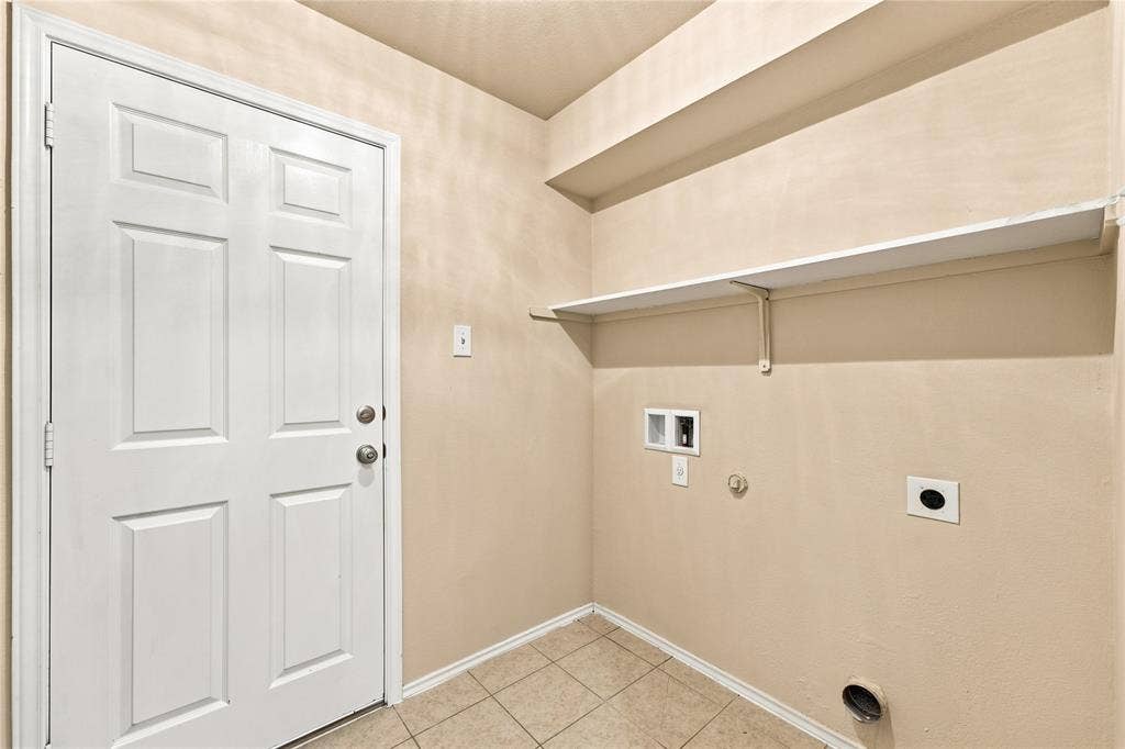 Dedicated laundry area featuring tile flooring, a white paneled door, and integrated shelving