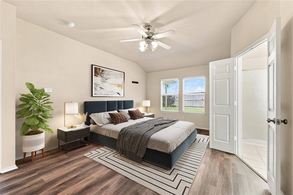 Spacious bedroom featuring wood-finish flooring, vaulted ceiling, and a ceiling fan