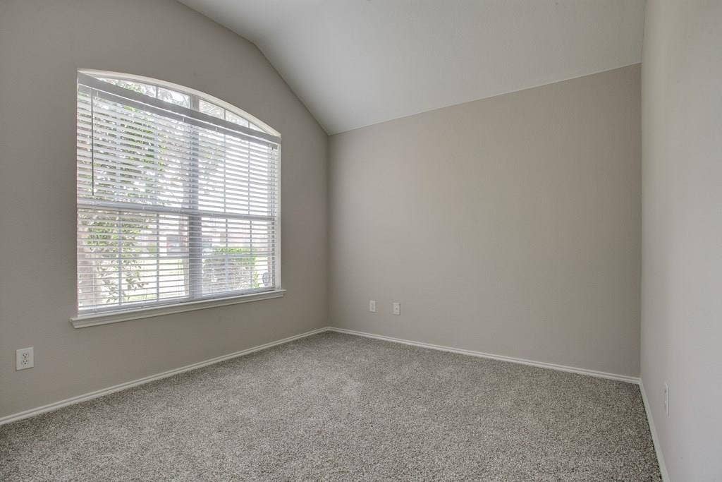 9213 Norfolk Lane, McKinney, TX 75071 Arched window with horizontal blinds, sloped ceiling, light gray wall paint, white baseboards, and gray speckled carpeting