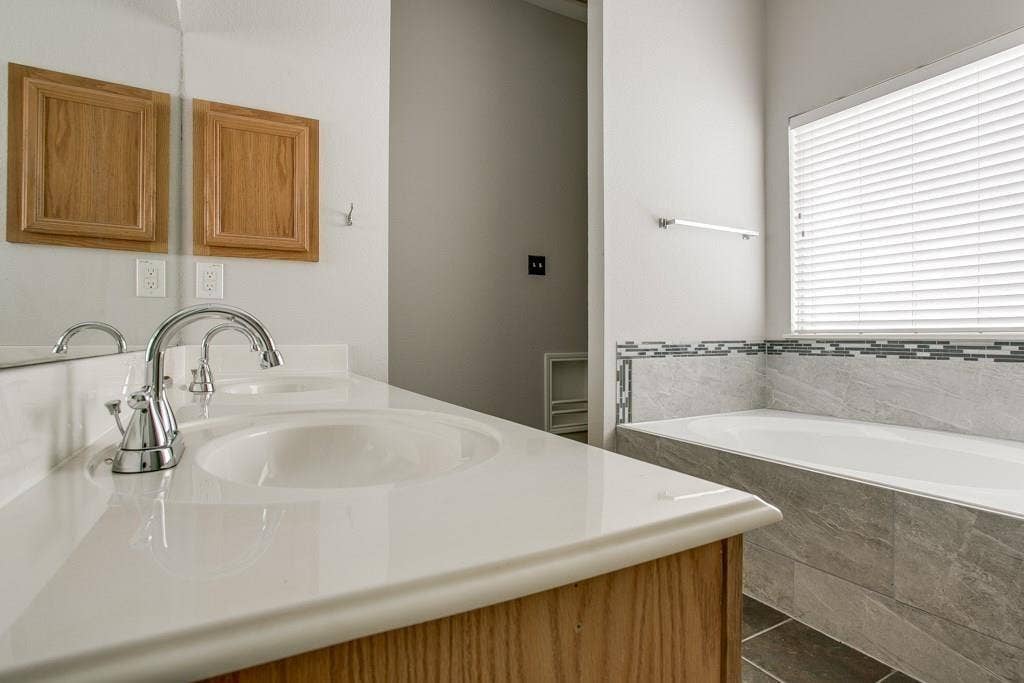 9213 Norfolk Lane, McKinney, TX 75071 Bathroom featuring a white countertop with an undermount sink, chrome faucet, and a large mirror
