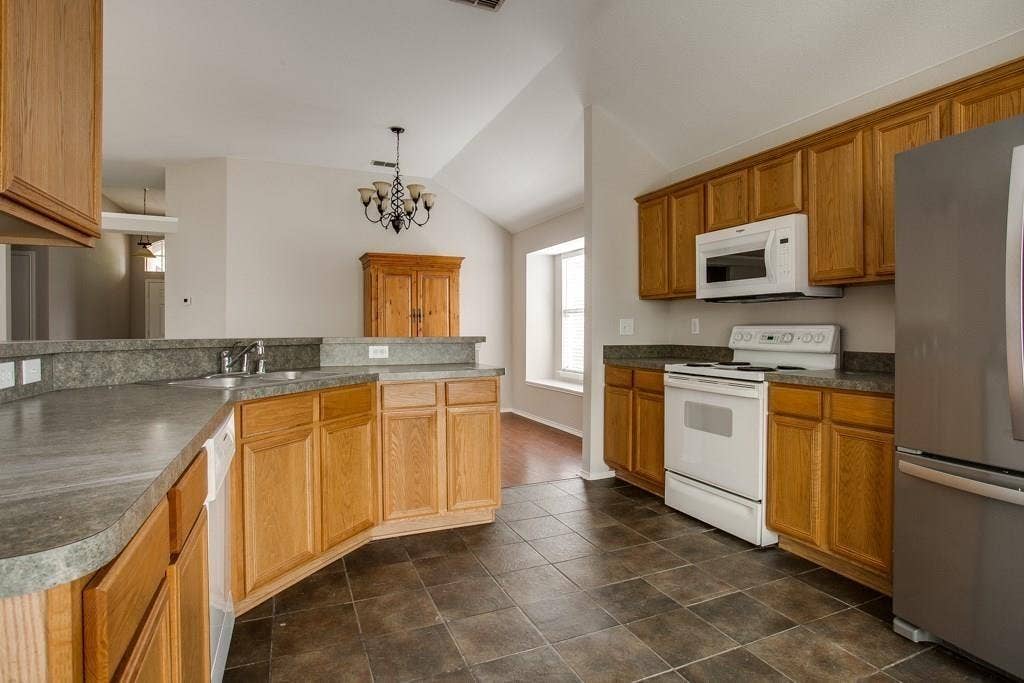 9213 Norfolk Lane, McKinney, TX 75071 Kitchen with wood cabinetry, dark tiled flooring, and light-toned countertops