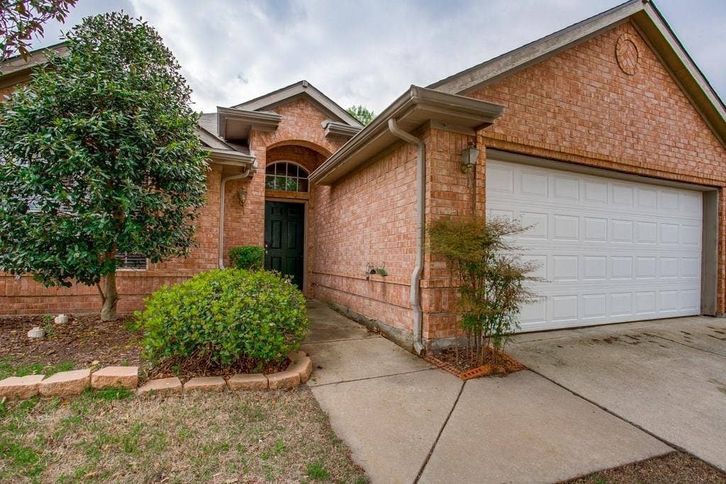 9213 Norfolk Lane, McKinney, TX 75071 Brick exterior featuring a two-car garage, arched entry, and a covered front porch