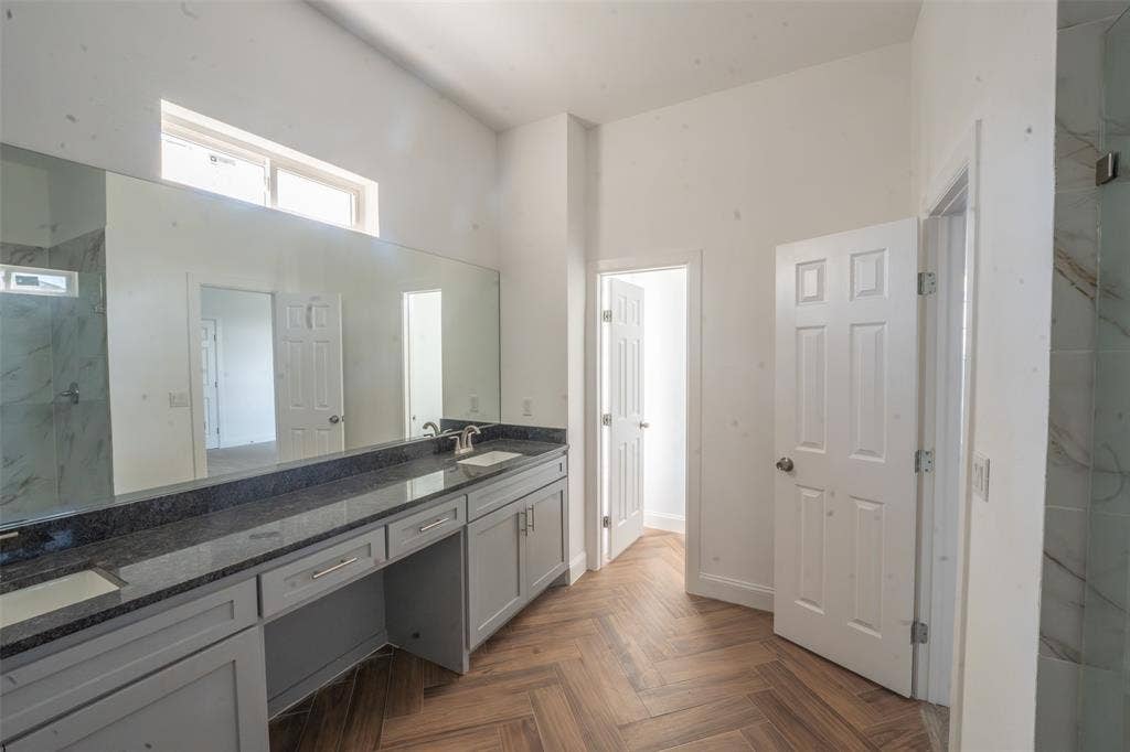 1408 Spinnaker Lane, Azle, TX 76020 Herringbone wood-finish flooring complements the spacious bathroom featuring a dual vanity with a dark countertop and light gray cabinetry
