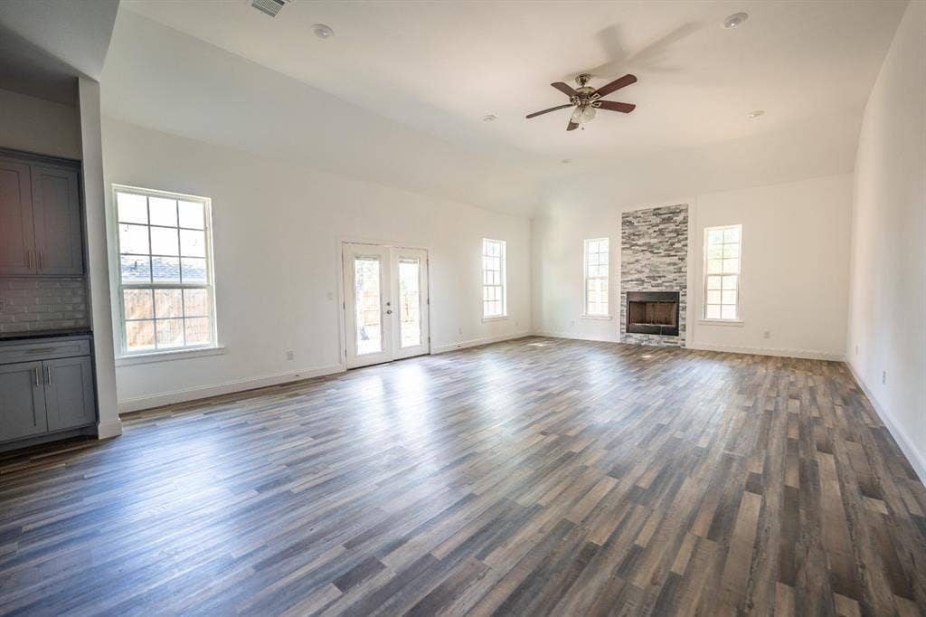 1408 Spinnaker Lane, Azle, TX 76020 Spacious living area featuring wood-finish flooring, vaulted ceilings, and a corner fireplace with stone surround