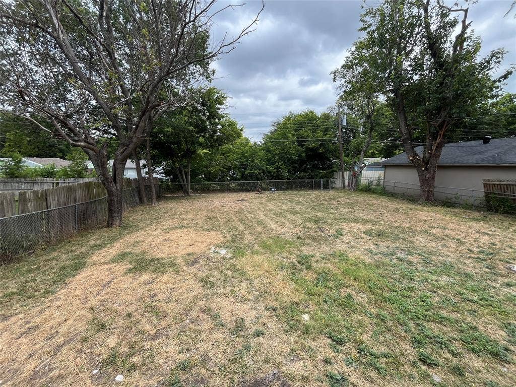 719 Fairwood Drive, Dallas, TX 75232 Expansive rear yard featuring a chain-link fence, mature trees, and a combination of natural ground cover and grass