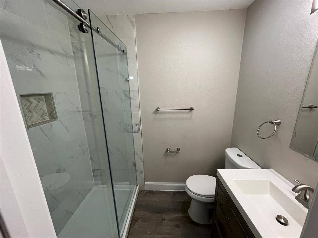 719 Fairwood Drive, Dallas, TX 75232 Contemporary bathroom featuring a spacious shower with sliding glass doors, white marble-look tile, and a recessed niche with herringbone pattern accent tile