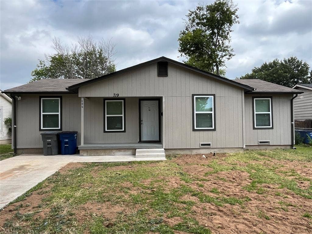 719 Fairwood Drive, Dallas, TX 75232 Single-story residence featuring light gray vertical panel siding with dark trim, a dark asphalt shingle roof, and a front concrete porch