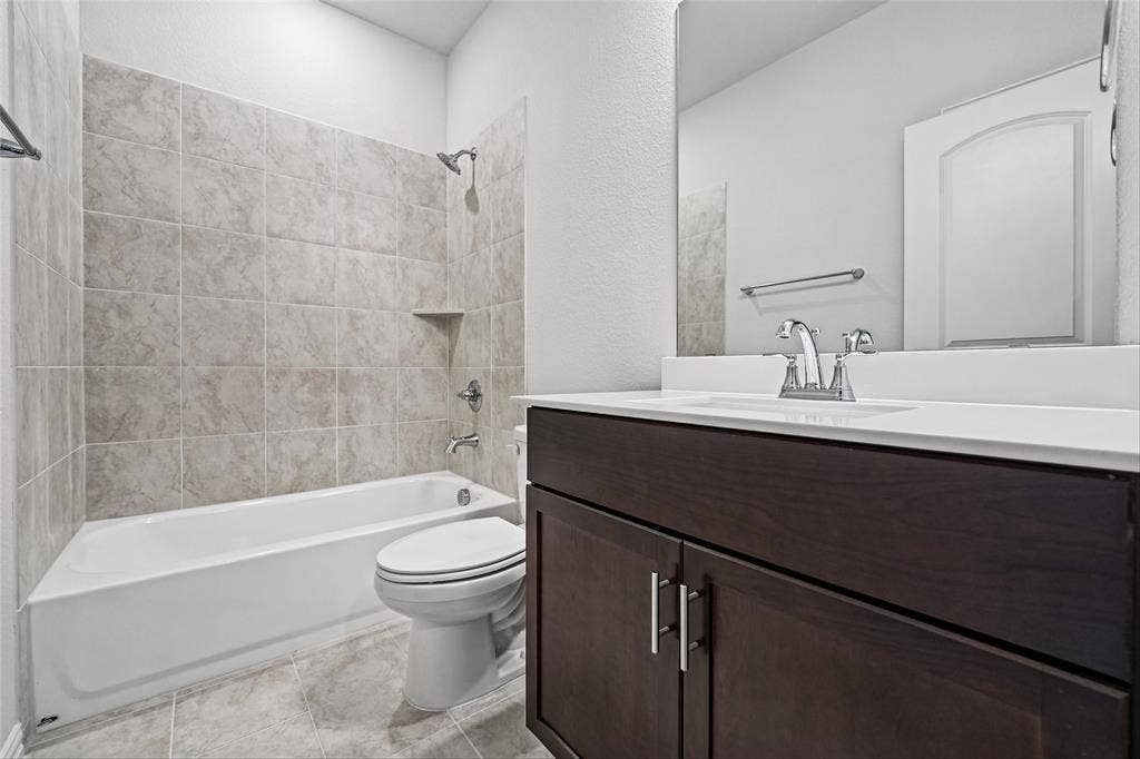 10008 Birchpoint Drive, Fort Worth, TX 76108 Bathtub with tiled surround, shower fixture, and an integrated shelf