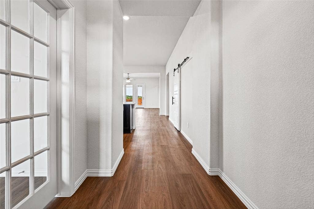 10008 Birchpoint Drive, Fort Worth, TX 76108 Wood-finish flooring throughout, white interior walls, and a white sliding barn door