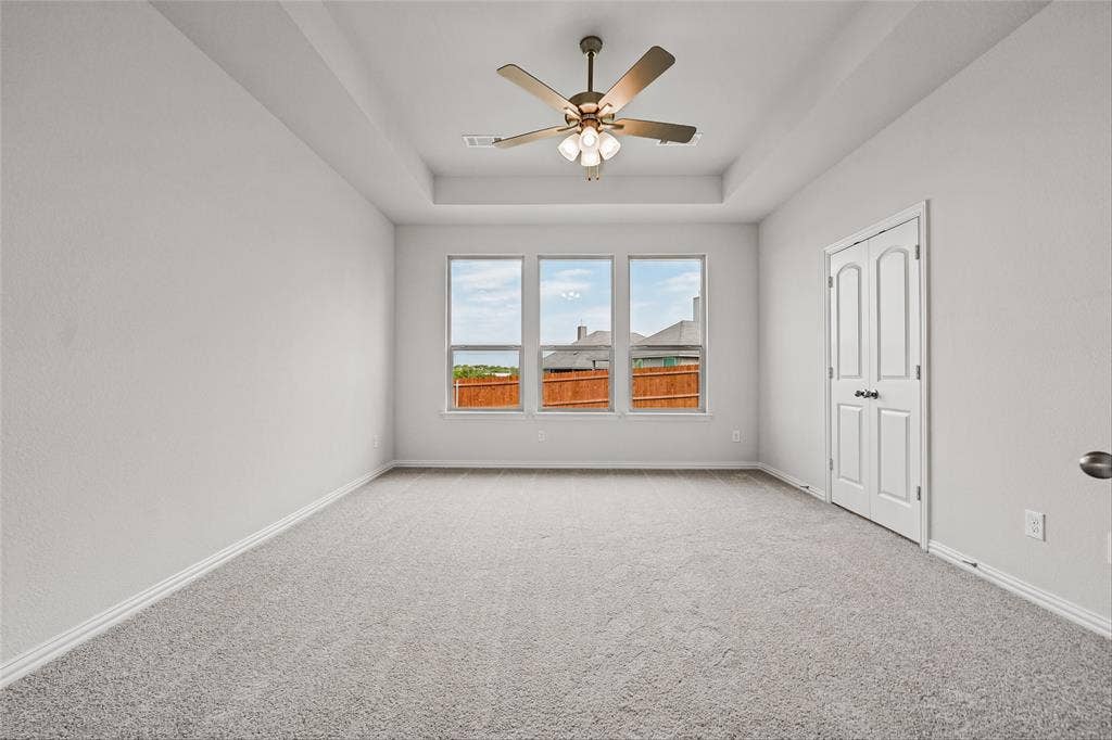 10008 Birchpoint Drive, Fort Worth, TX 76108 Recessed ceiling, ceiling fan with integrated lighting, three large windows, light gray carpet, and white trim