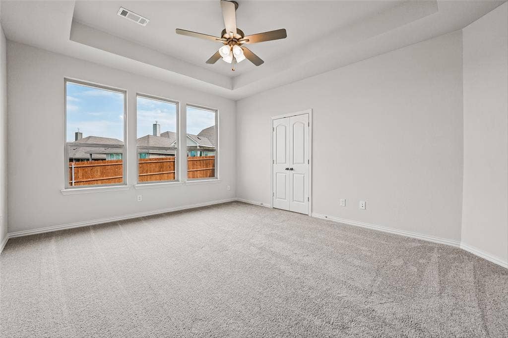 10008 Birchpoint Drive, Fort Worth, TX 76108 Tray ceiling with a ceiling fan, three pane windows, and light gray wall-to-wall carpeting