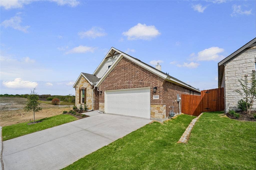 10008 Birchpoint Drive, Fort Worth, TX 76108 Brick and stone exterior with a gabled roofline, attached garage, concrete driveway, and manicured lawn