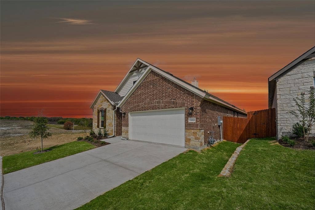 10008 Birchpoint Drive, Fort Worth, TX 76108 Brick and stone exterior with an attached garage, concrete driveway, and manicured landscaping