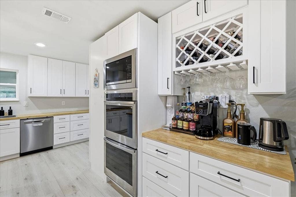 3533 Granada Drive, Richland Hills, TX 76118 coffee bar and built in glassware hang-downs next to the stacked double ovens and microwave.