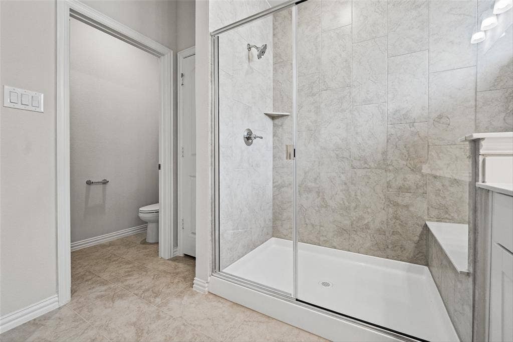 10004 Birchpoint Drive, Fort Worth, TX 76108 Walk-in shower with clear glass enclosure, tiled walls, and an integrated shower bench