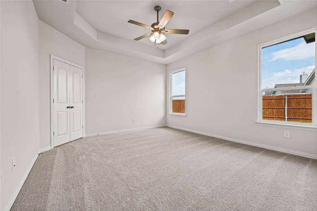 10004 Birchpoint Drive, Fort Worth, TX 76108 Recessed tray ceiling with a ceiling fan, light gray carpet flooring, and two windows