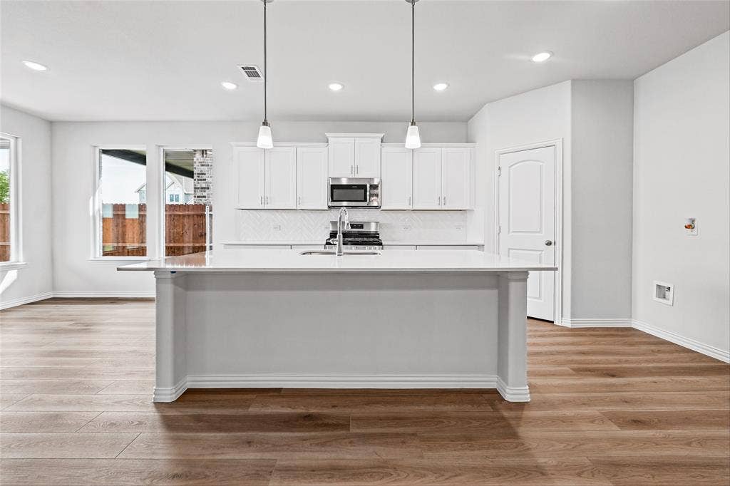 10004 Birchpoint Drive, Fort Worth, TX 76108 Kitchen with a center island, white cabinetry, integrated stainless steel appliances, and wood-finish flooring