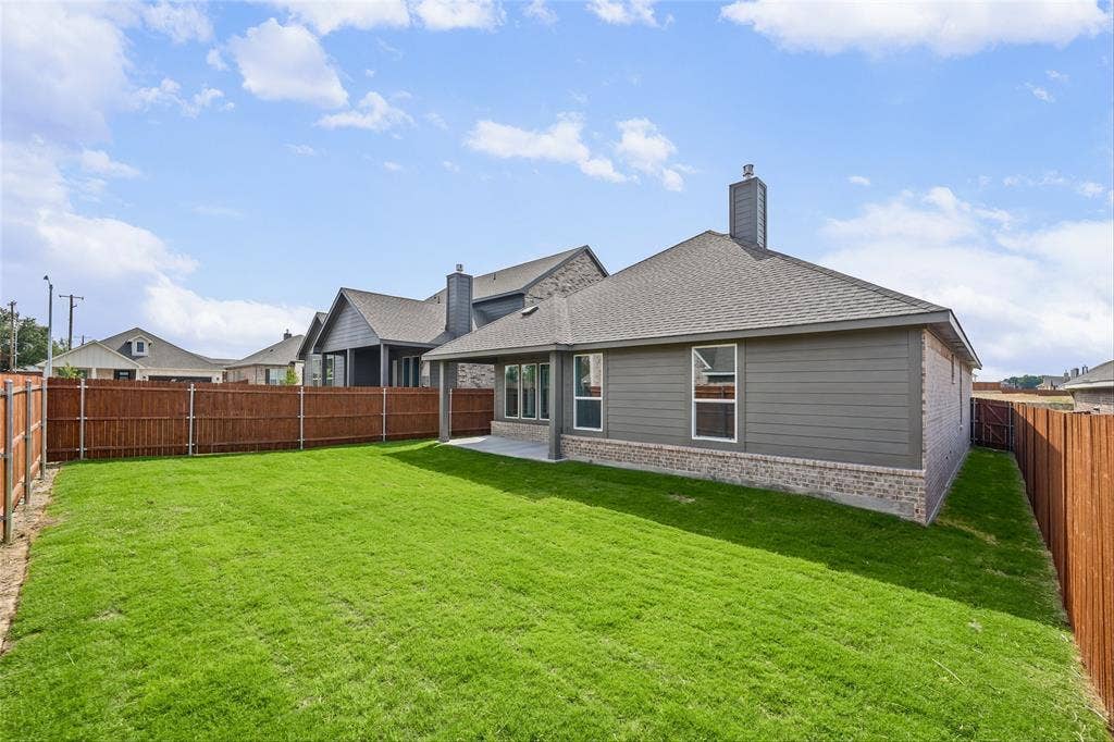 10004 Birchpoint Drive, Fort Worth, TX 76108 Expansive backyard featuring a manicured lawn, wood privacy fencing, a covered concrete patio, and a shingled roofline
