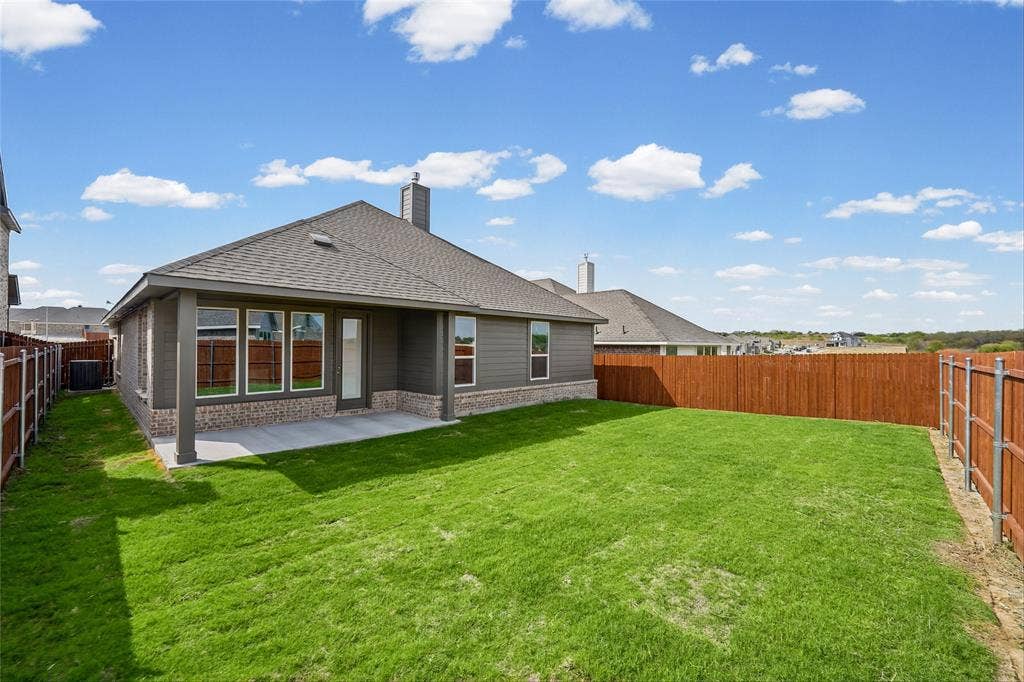 10004 Birchpoint Drive, Fort Worth, TX 76108 Expansive green lawn with a privacy fence, covered patio, and a shingled roofline