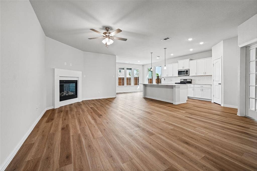10004 Birchpoint Drive, Fort Worth, TX 76108 Open-concept living space featuring wood-finish flooring, a corner fireplace, and a ceiling fan