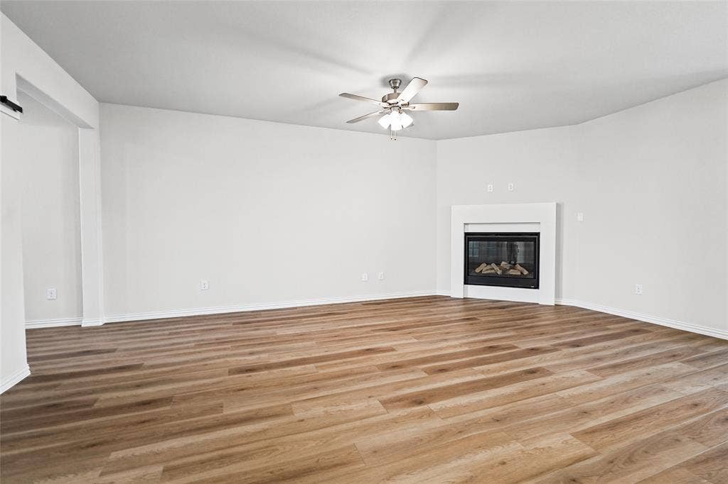 10004 Birchpoint Drive, Fort Worth, TX 76108 Wood-finish flooring, built-in fireplace, ceiling fan with integrated lighting, and crisp white walls